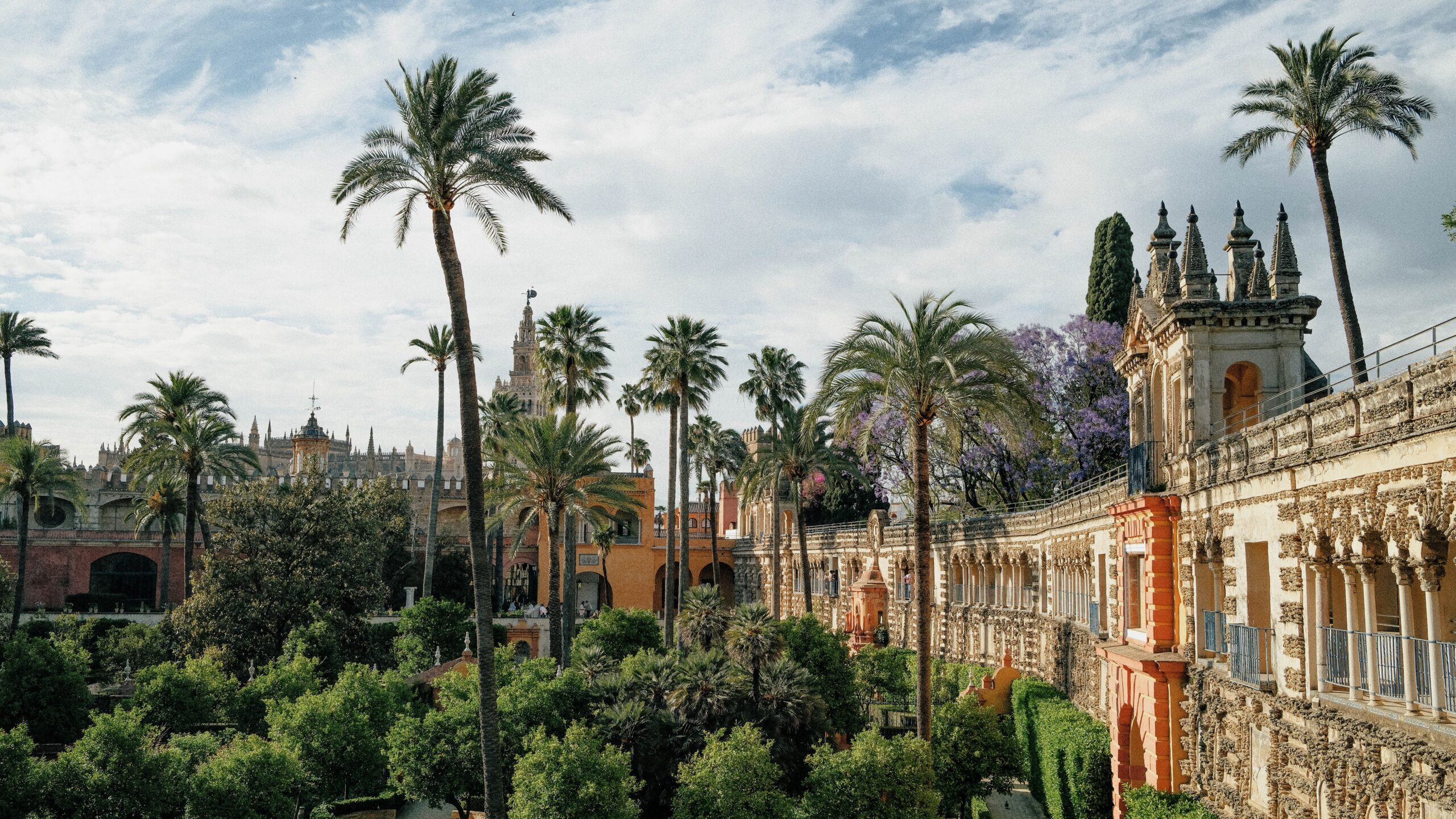 Vista panorámica de los exuberantes jardines verdes, palmeras y arquitectura histórica del Real Alcázar de Sevilla. Foto de Katerina Kerdi en Pexels.