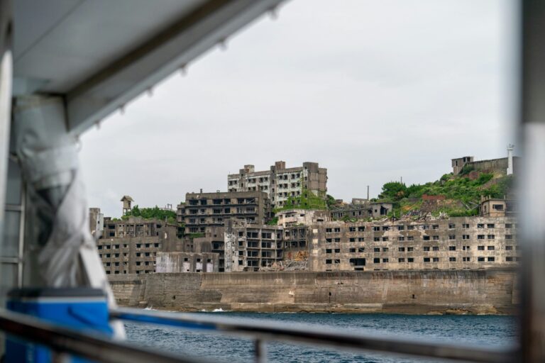Vista desde un barco de los edificios abandonados y en ruinas de hormigón gris en la isla de Hashima (Gunkanjima), Nagasaki, Japón.
